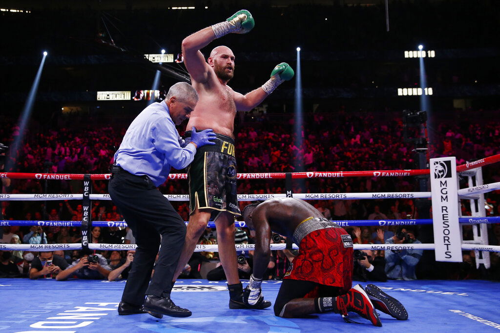 Tyson Fury, of England, knocks down Deontay Wilder in a heavyweight championship boxing match.