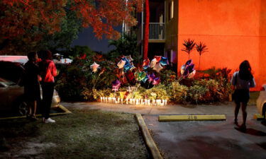 People stand near the memorial on the spot where 18-year-old Dwight "DJ" Grant's body was found near his home on October 26 in Miramar