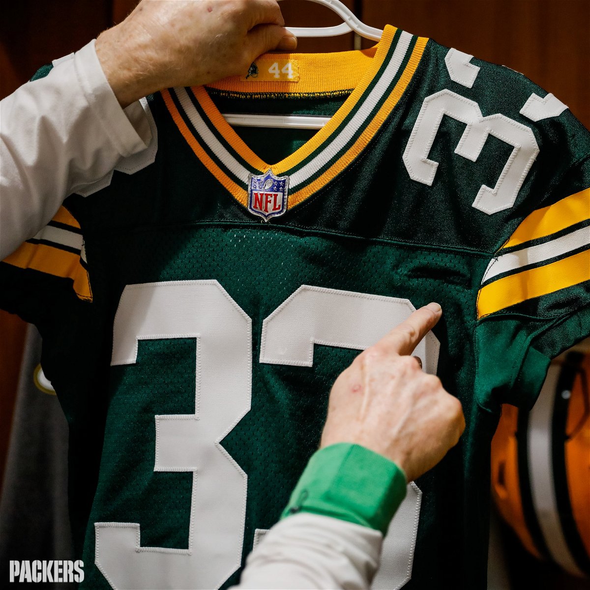 A Packers staff member points to pocket added to Aaron Jones' jersey.
