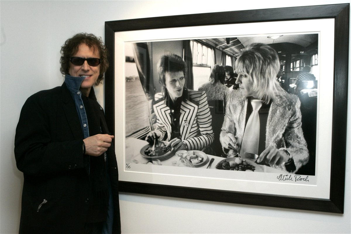 <i>J. Vespa/WireImage for Peoples Revolution/Getty Images</i><br/>Mick Rock with his photo of David Bowie and Mick Ronson.