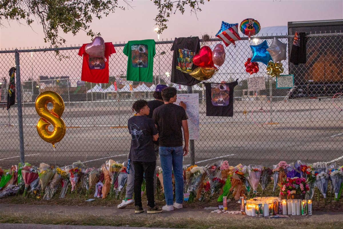 <i>Thomas Shea/AFP/Getty Images</i><br/>Concert attendees Isaac Hernandez and Matthias Coronel watch Jesus Martinez sign a remembrance board at a makeshift memorial on November 7