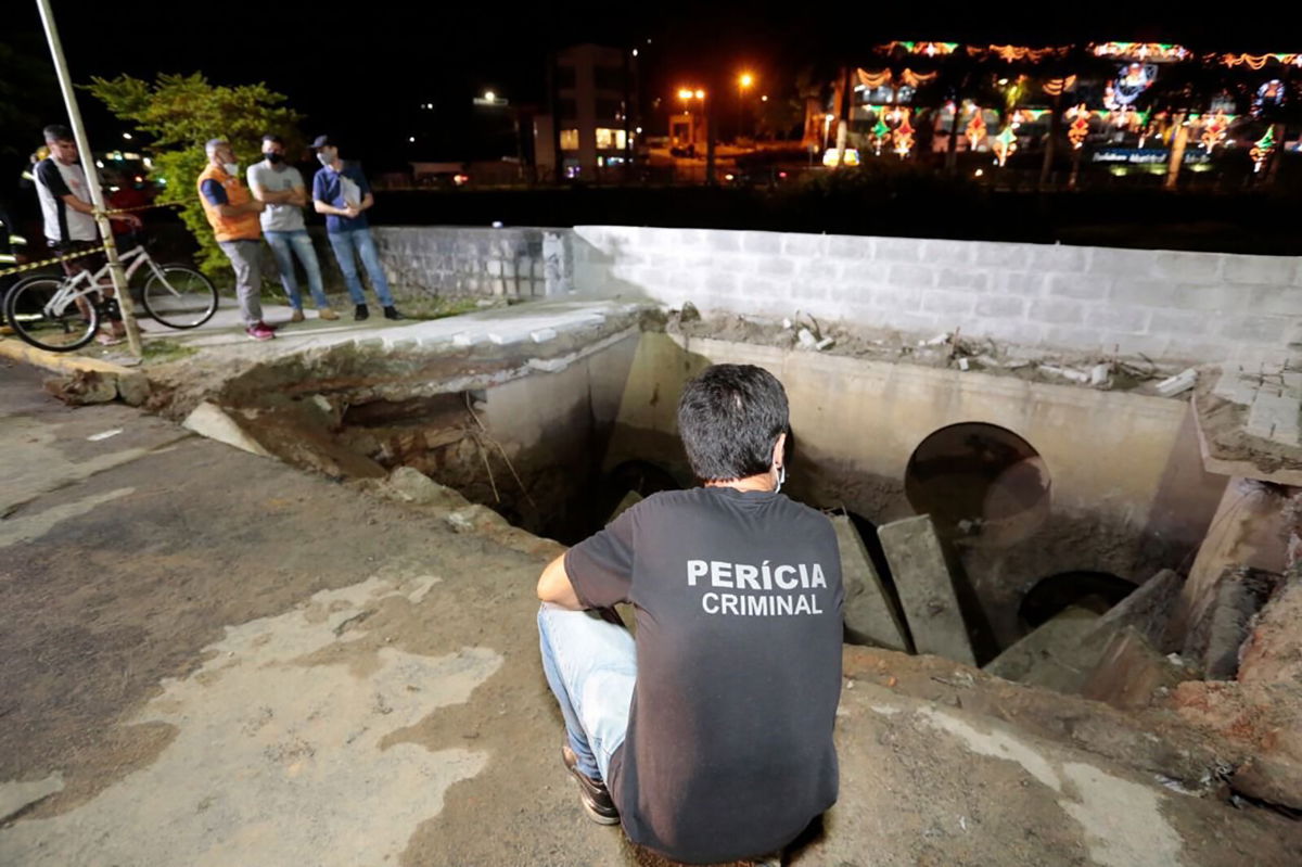 <i>CNN Brasil/Joinville City Hall</i><br/>Officials survey the scene after a sidewalk collapsed in the city of Joinville on Monday.