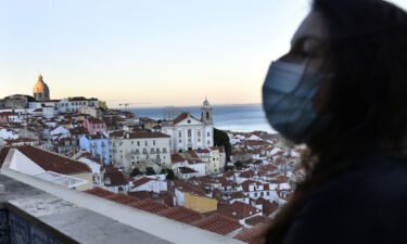 A person wearing a protective mask observes the city of Lisbon from the Santa Luzia viewpoint in Portugal.
