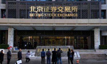Journalists film workers installing the nameplate of Beijing Stock Exchange on Financial Street in Beijing