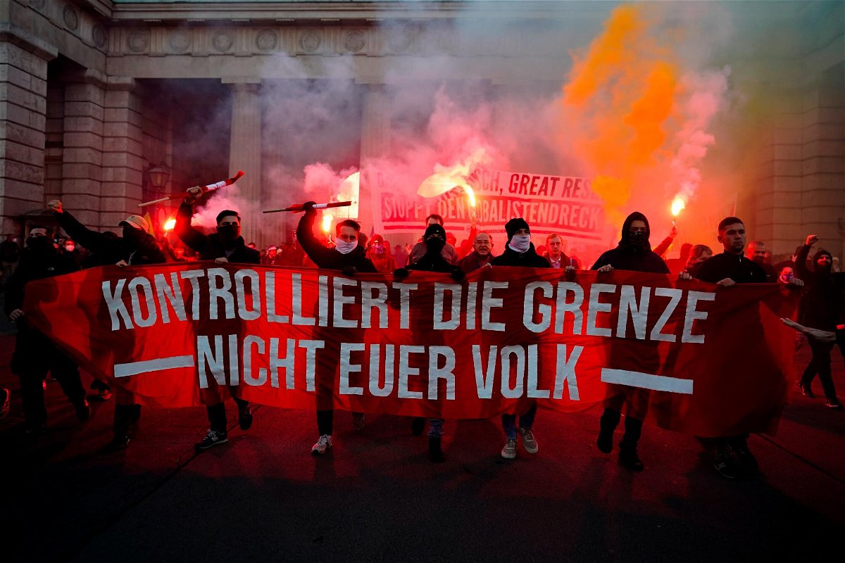 <i>Florian Schroetter/AP</i><br/>Crowds shout slogans and light flares during a demonstration against Austria's Covid restrictions as the banner reads: 