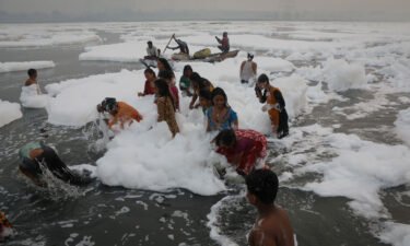 People bathe amidst toxic foam covering the Yamuna river on a smoggy morning in New Delhi