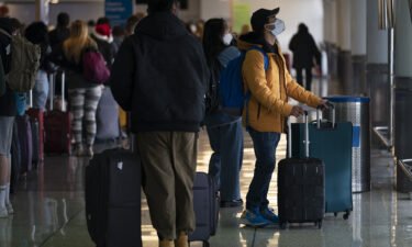 Omicron isn't hurting travel stocks. Travelers are seen here looking at the arrival and departure screens at the Los Angeles International Airport in Los Angeles on December 20.