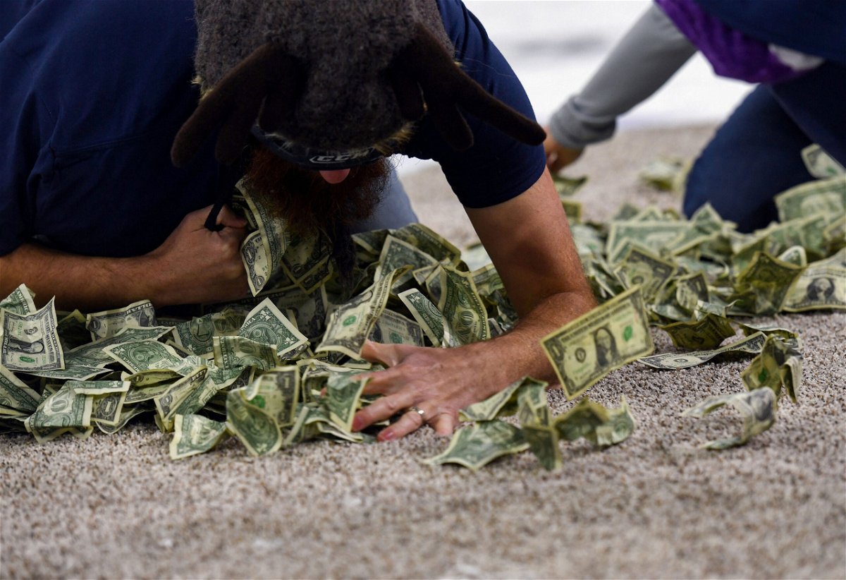 <i>Erin Woodiel/Argus Leader/USA Today Network</i><br/>A teacher shovels dollar bills into his shirt during the 