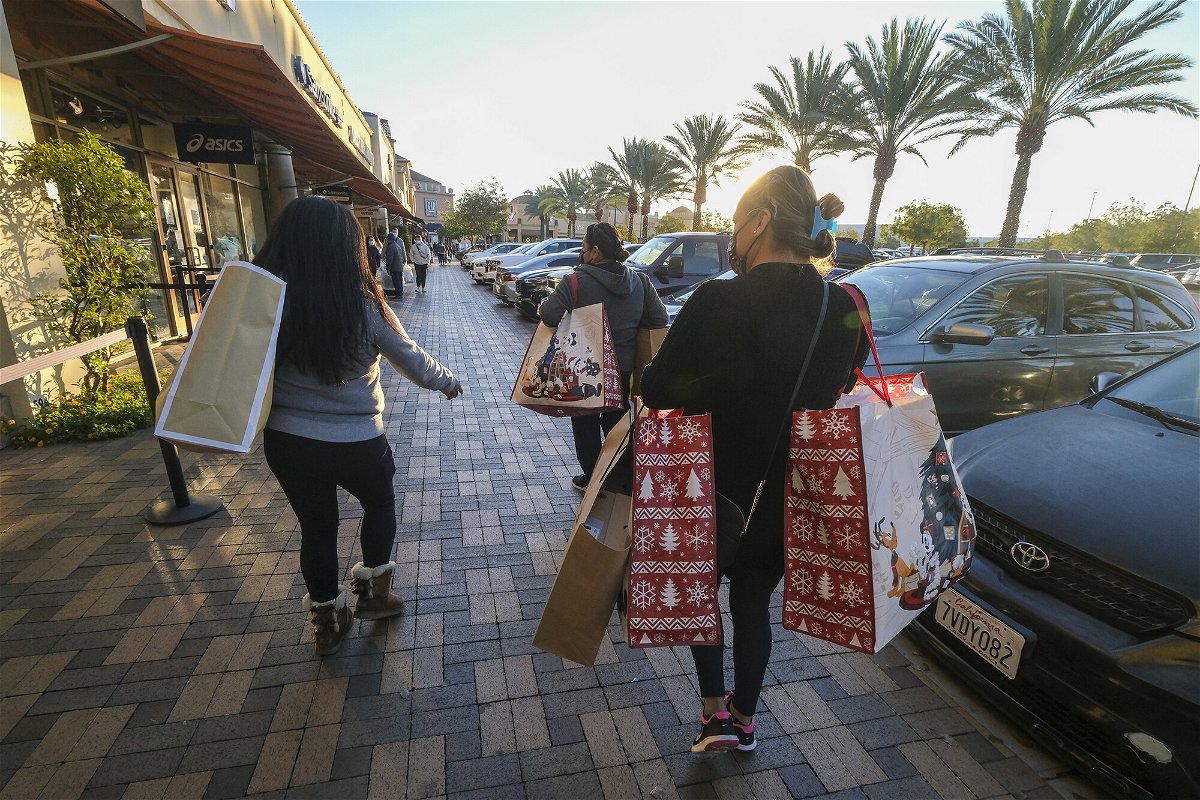<i>Ringo H.W. Chiu/AP</i><br/>Black Friday shoppers wearing face masks carry bags at the Citadel Outlets in Commerce