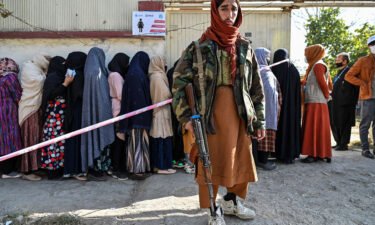 A Taliban fighter stands guard as women wait in line for food from the World Food Programme in Kabul on November 6.