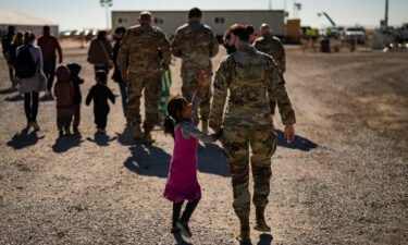 A U.S. military service member hold the hands of an Afghan girl at Holloman Air Force Base in Alamogordo