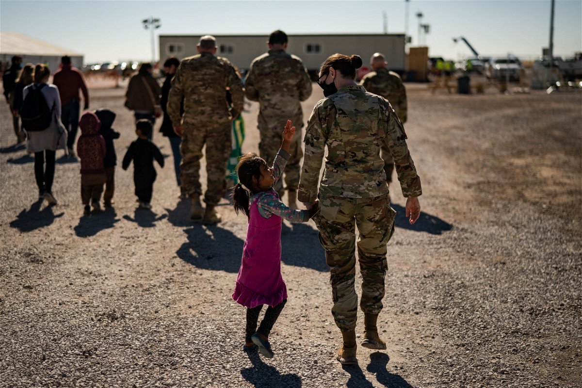 <i>Salwan Georges/The Washington Post/Getty Images</i><br/>A U.S. military service member hold the hands of an Afghan girl at Holloman Air Force Base in Alamogordo.