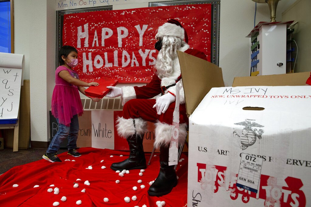 U.S. Marine Corps Staff Sgt. Federico Gomez, dressed as Santa Claus, hands a gift to a student in Shungnak, Alaska.