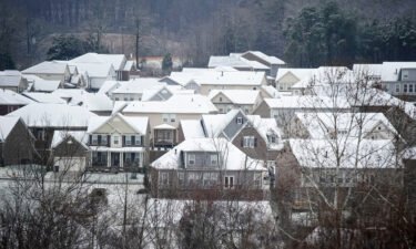 Winter storms and spiking energy prices could lead to record high heating bills. Snow and rain fall on rooftops of houses Sunday