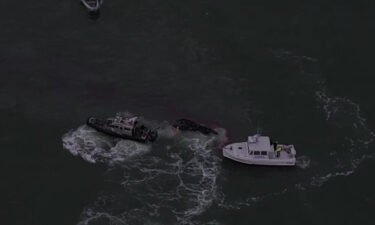 Rescuers work to save three fishermen who held on to debris surrounded by a slick of diesel fuel after their 55-foot boat sank on Tuesday.