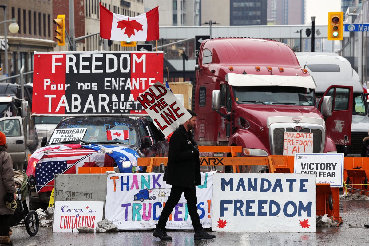 <i>DAVE CHAN/AFP/AFP via Getty Images</i><br/>A protester walks in front of parked trucks on February 8 as demonstrators in Ottawa