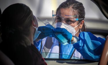 A healthcare worker Desirae Velasquez administers a COVID19 test to Maria Lemus at a testing facility established by Total Testing Solutions in Boyle Heights on Tuesday