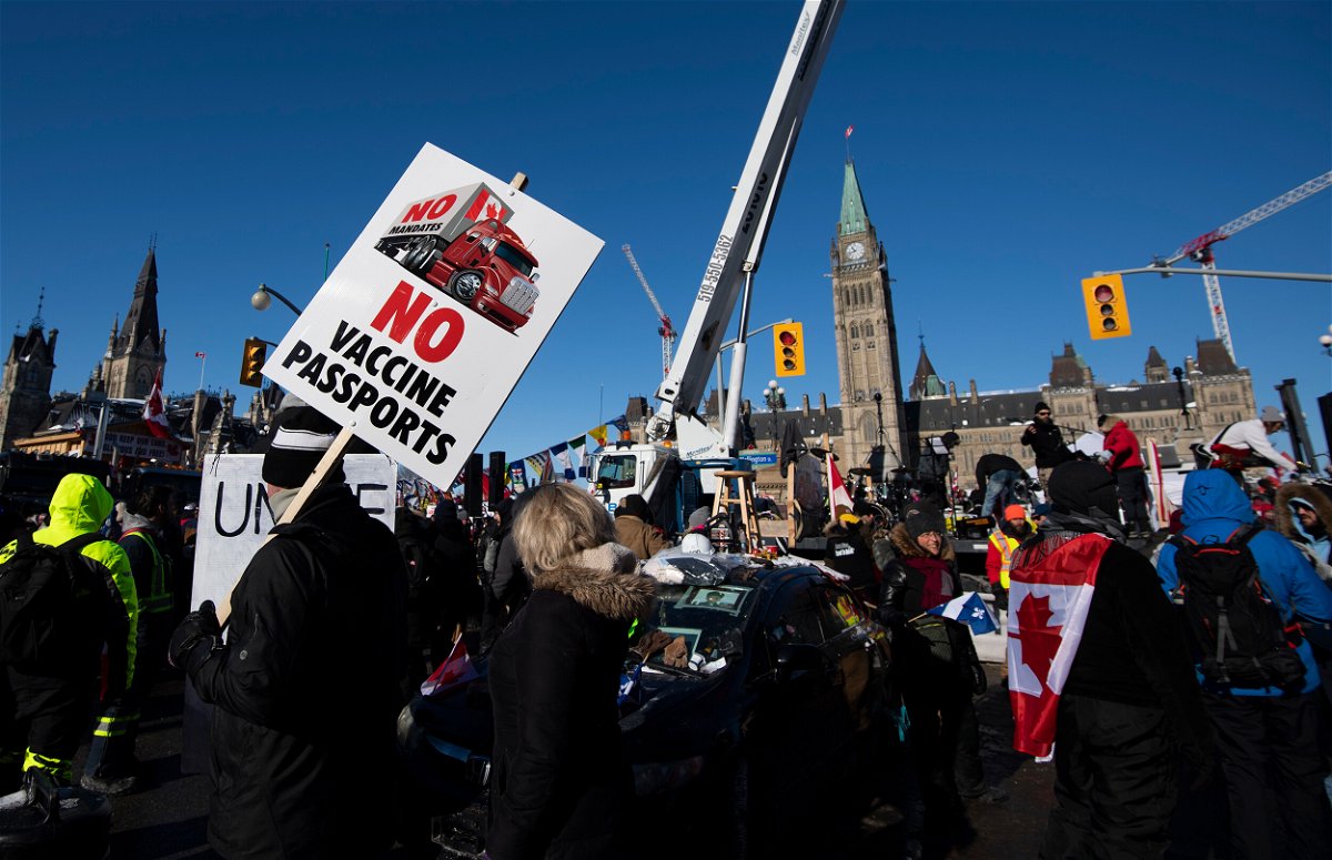 <i>Justin Tang/The Canadian Press/AP</i><br/>People hold signs and wave flags along Wellington Street in front of Parliament Hill as a protest against COVID-19 restrictions that has gridlocked downtown Ottawa continues into its second week