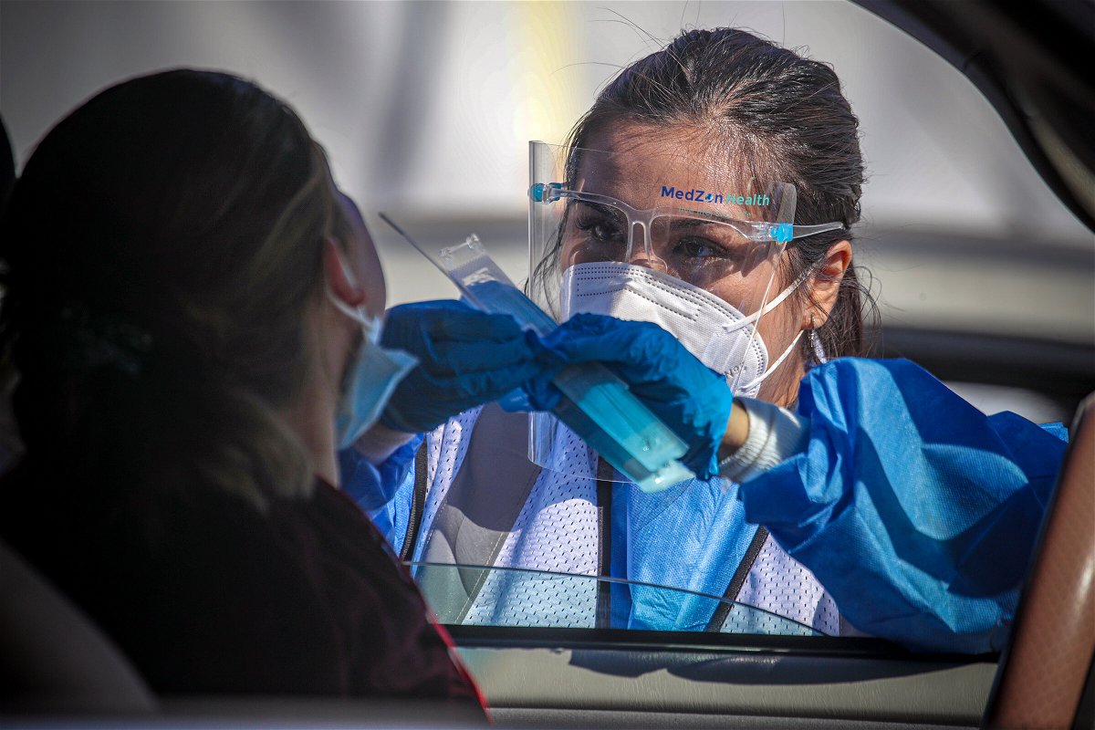 <i>Irfan Khan/Los Angeles Times/Getty Images</i><br/>A healthcare worker Desirae Velasquez administers a Covid-19 test to Maria Lemus at a testing facility in Los Angeles
