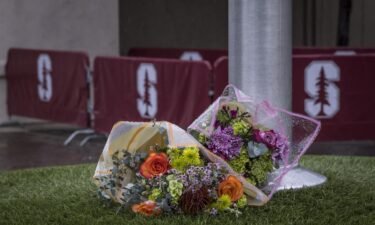 A bouquet of flowers lies at the base of a flagpole outside Maloney Field at Laird Q. Cagan Stadium where at Stanford University soccer players practiced in Stanford