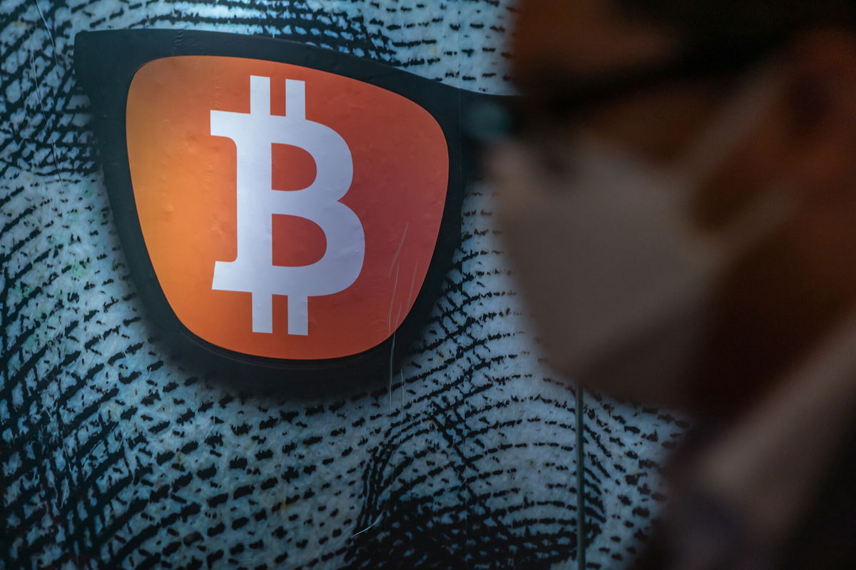 <i>Anthony Kwan/Getty Images</i><br/>Pedestrians walk past a display of cryptocurrency Bitcoin on February 15