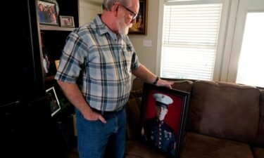 Joey Reed holds a portrait of his son Marine veteran and Russian prisoner Trevor Reed at his home in Fort Worth