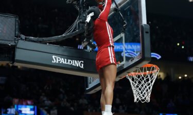 Indiana cheerleader Cassidy Cerny is lifted up to retrieve a basketball that became stuck at the top of the backboard.