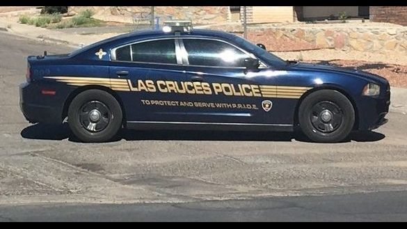 A Las Cruces police squad car sits parked near a brick wall.