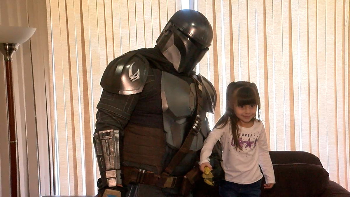 Little girl embraces man dressed up as The Mandalorian