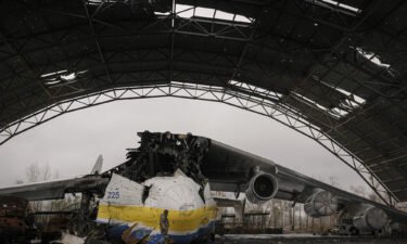A Ukrainian serviceman walks past an Antonov An-225 aircraft destroyed during fighting between Russian and Ukrainian forces