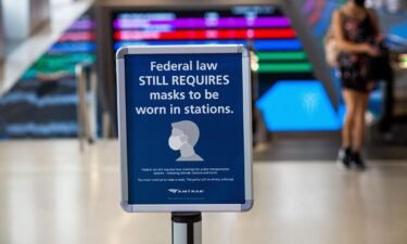A woman walks past a sign calling for mask wearing at Penn station in New York on August 2