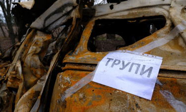 A sign taped to a burned out car reads "corpses" in Ukrainian