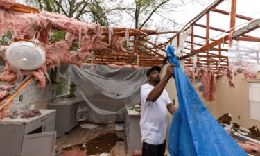 Khary Johnson places tarps on the roof of a damaged home after a tornado passed through an area in Allendale