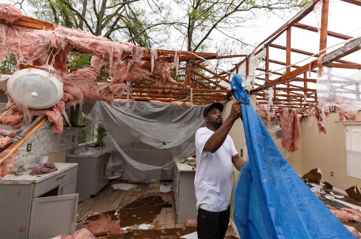 <i>SAM WOLFE/REUTERS</i><br/>Khary Johnson places tarps on the roof of a damaged home after a tornado passed through an area in Allendale