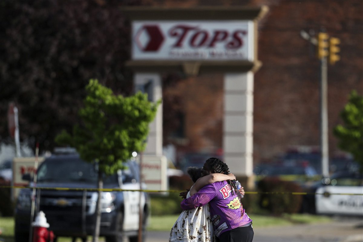 <i>Joshua Bessex/AP</i><br/>People hug near the scene of the mass shooting at the Tops Friendly Markets store on May 14.