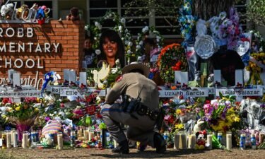 A police officer clears the makeshift memorial before the visit of President Joe Biden at Robb Elementary School in Uvalde