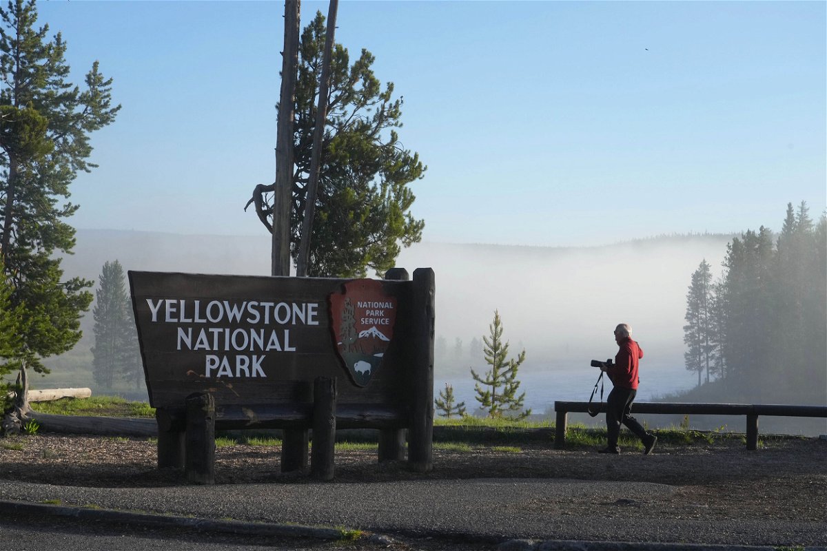 <i>George Frey/Getty Images</i><br/>A man takes a picture at the south entrance of Yellowstone National Park