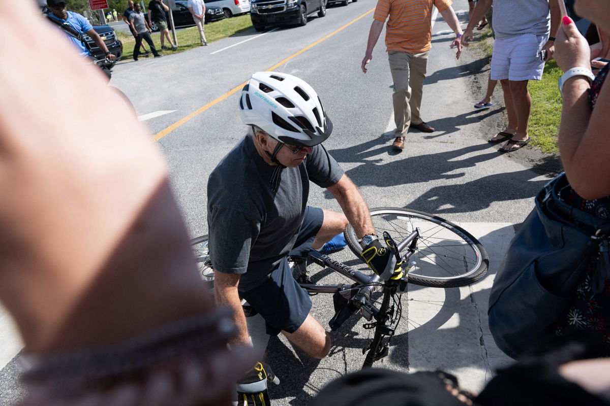 <i>Saul Loeb/AFP/Getty Images</i><br />US President Joe Biden falls off his bicycle as he approaches well-wishers following a bike ride at Gordon's Pond State Park in Rehoboth Beach