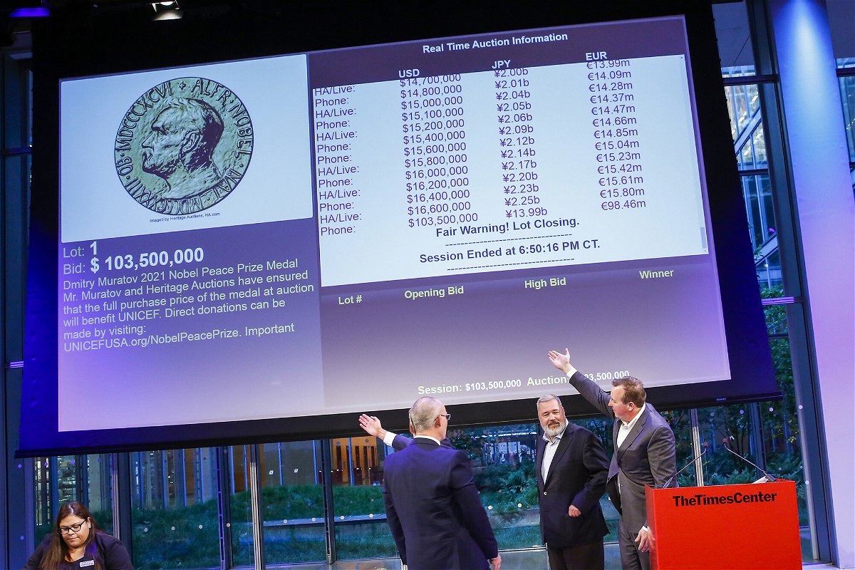 <i>Eduardo Munoz Alvarez/AP</i><br/>People point to the screen that shows the final price of $103.5 million for Russian journalist Dmitry Muratov's 23-karat gold medal of the 2021 Nobel Peace Prize after being auctioned at the Times Center