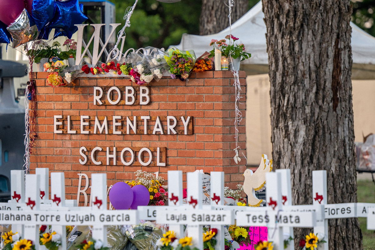 <i>Brandon Bell/Getty Images North America/Getty Images</i><br/>A memorial is seen surrounding the Robb Elementary School sign following the mass shooting at Robb Elementary School on May 26 in Uvalde