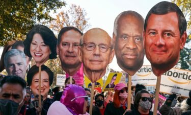 Activists with The Center for Popular Democracy Action hold photos of U.S. Supreme Court justices as they block an intersection during a demonstration in front of the U.S. Supreme Court on December 1