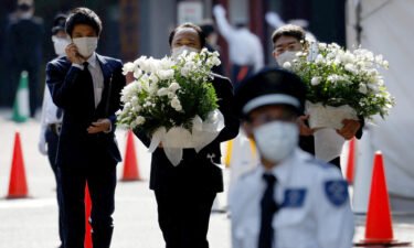 Officials carry flowers inside Zojoji Temple
