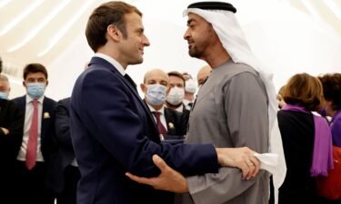 French President Emmanuel Macron (L) is greeted by Abu Dhabi's Crown Prince Mohammed bin Zayed al-Nahyan during his tour of the Emirates pavillion at the Dubai Expo on the first day of his Gulf tour on December 3