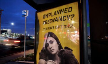 A billboard advertising adoption services targets pregnant women at a bus stop in Oklahoma City