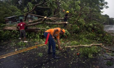 Civil defense personnel and firefighters are pictured here working to remove fallen trees from the highway connecting the provinces of Maria Trinidad Sanchez and Samana
