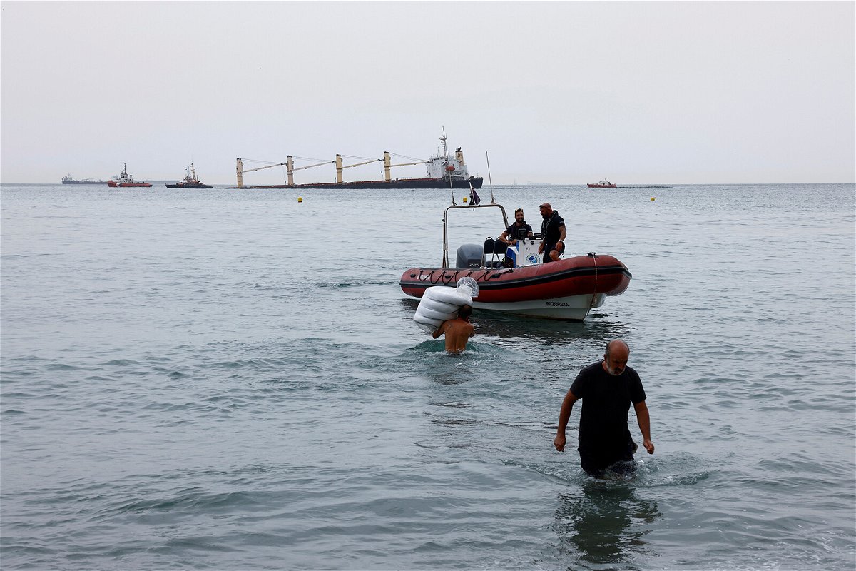 <i>Jon Nazca/Reuters</i><br/>Workers carry floats to contain oil from the cargo ship OS 35