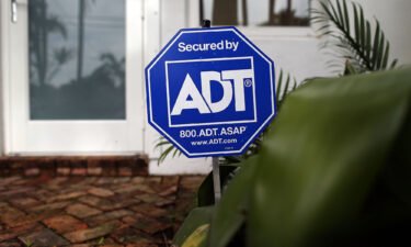 State Farm is making a $1.2 billion investment in ADT. An ADT home security alarm sign is seen in front of a Miami home in 2016.