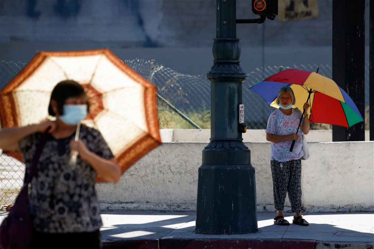 <i>Caroline Brehman/EPA-EFE/Shutterstock/Shutterstock/CAROLINE BREHMAN/EPA-EFE/Shutterstock</i><br/>People walk with umbrellas for shade in Los Angeles on September 1.