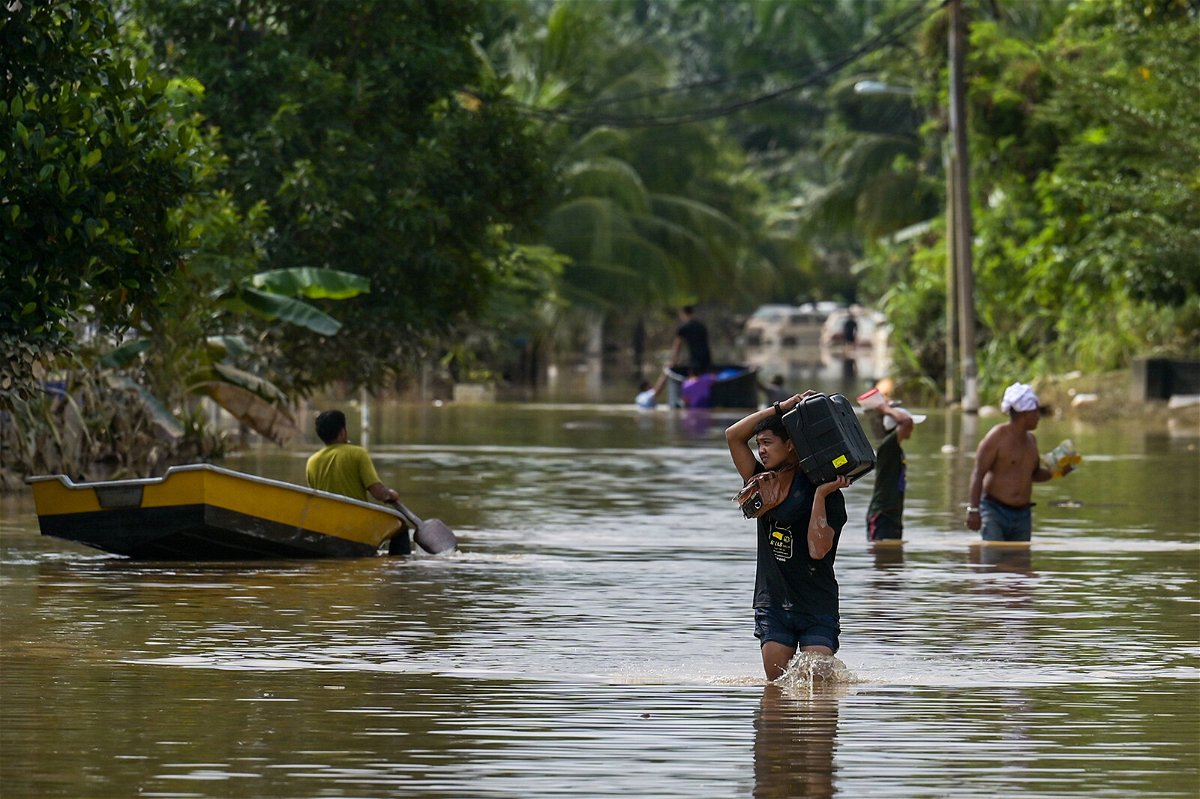 <i>Mohd Rasfan/AFP/Getty Images</i><br/>Residents walk through floodwaters in Malaysia's Pahang state in January 2021.
