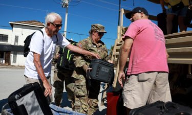 Florida Army National Guard members help Tim Tuitt (L) and John Davis as they are evacuated from Fort Myers Beach in the wake of Hurricane Ian.